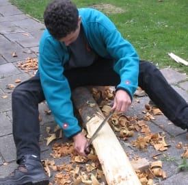 Jan van der Veen, schrijver van Houtkoorts: Zelf een handboog maken, prepareert een stuk hout om tot een boog te maken.